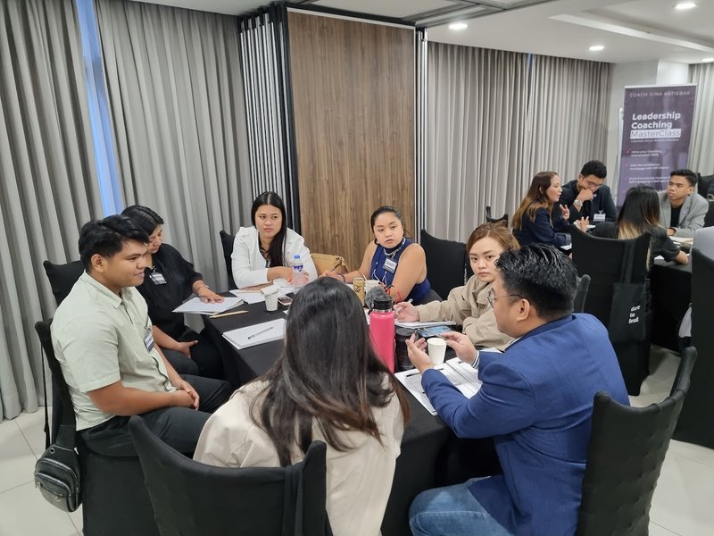 Workshop participants practice paired coaching at a table during a Leadership Coaching MasterClass breakout.