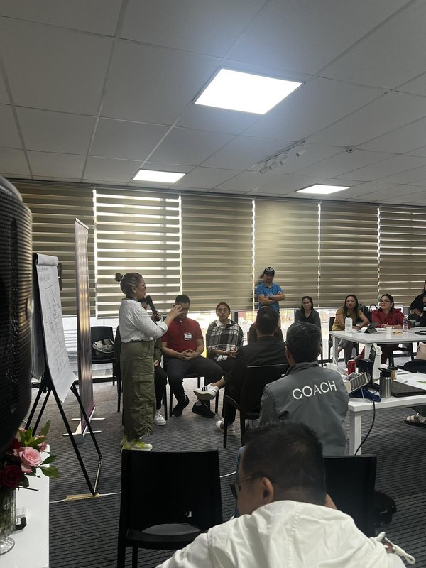 Coach Gina Katigbak works closely with participants in a coaching circle with a microphone in hand.